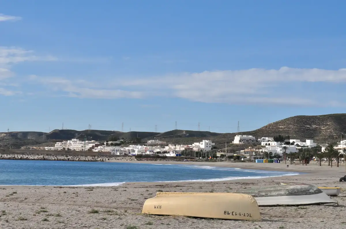 Playa urbana de Carboneras con barcas varadas y el pueblo blanco al fondo