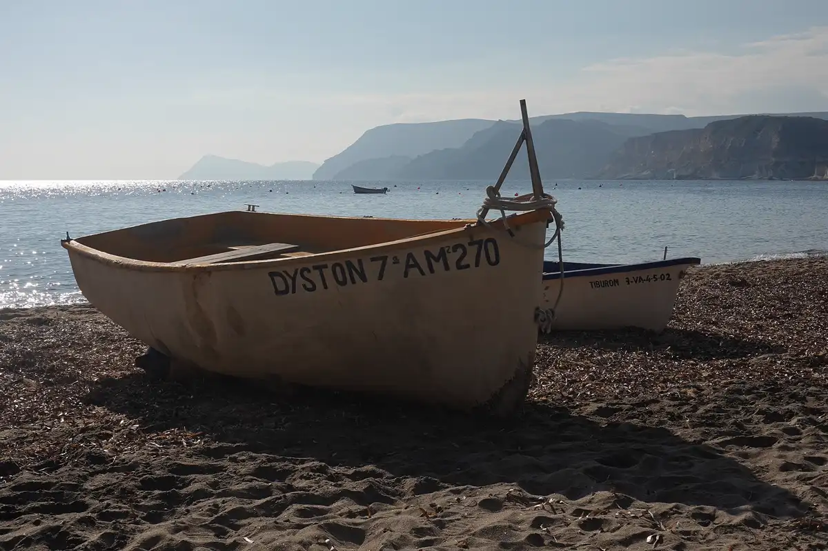Barcas de pesca en la arena de la playa de Agua Amarga, con la Punta de la Polacra al fondo