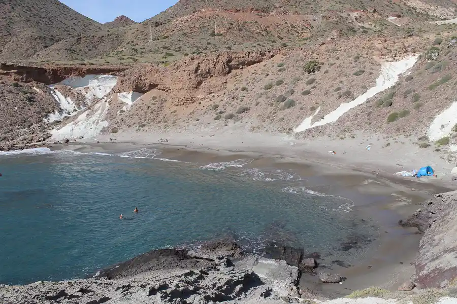 Cala Rajá, pequeña cala de grava entre laderas rojizas del Parque Natural